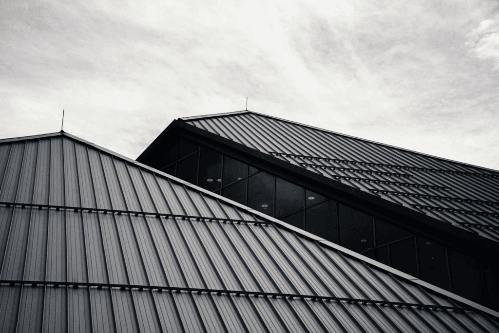 Sleek glass commercial building topped with a sturdy metal roof reflecting the sky.