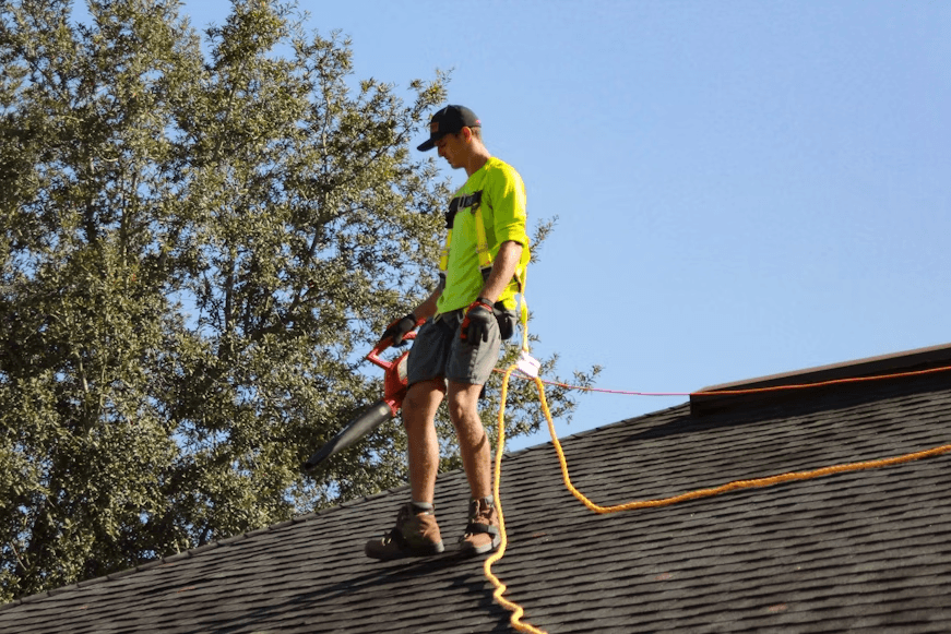 a man tied to a rope working on top of a roof