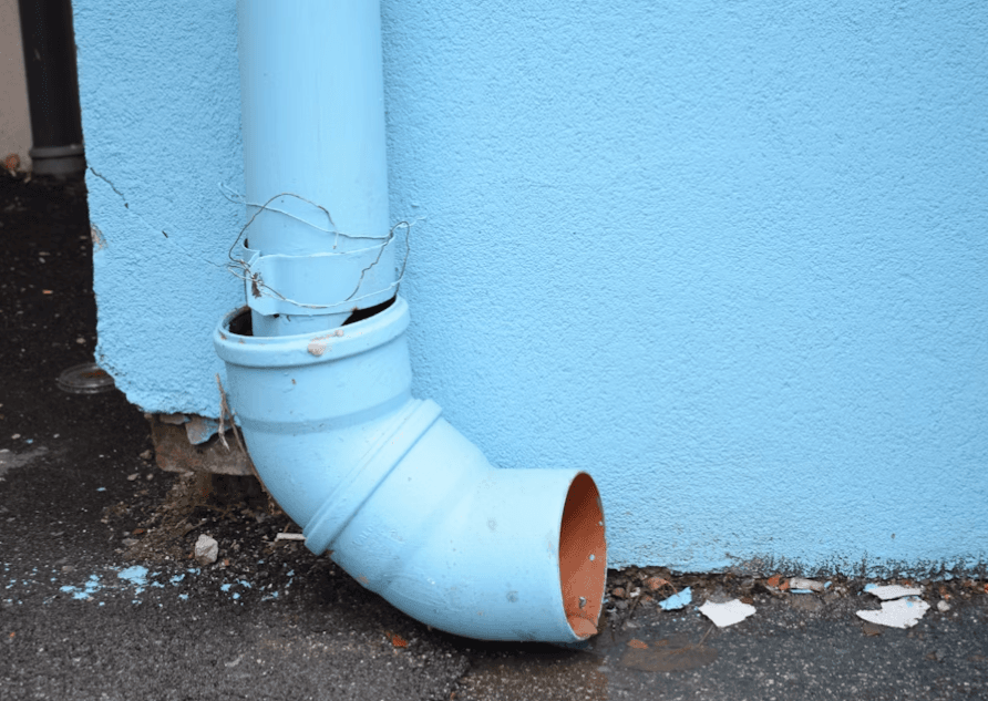 This image shows a blue gutter pipe near a blue wall.