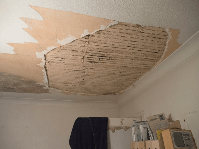 This photo shows a damaged ceiling exposing poor insulation