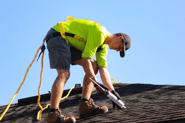 This photo shows a roofer repairing a damaged roof to prevent costly issues