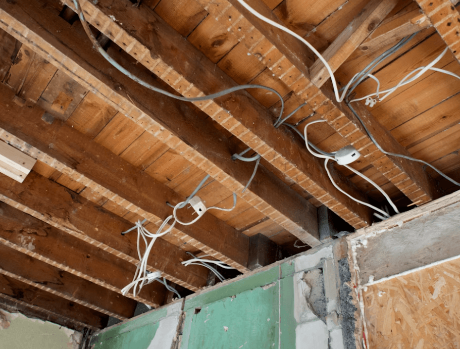 This image shows white electrical wires on a brown wooden roof.