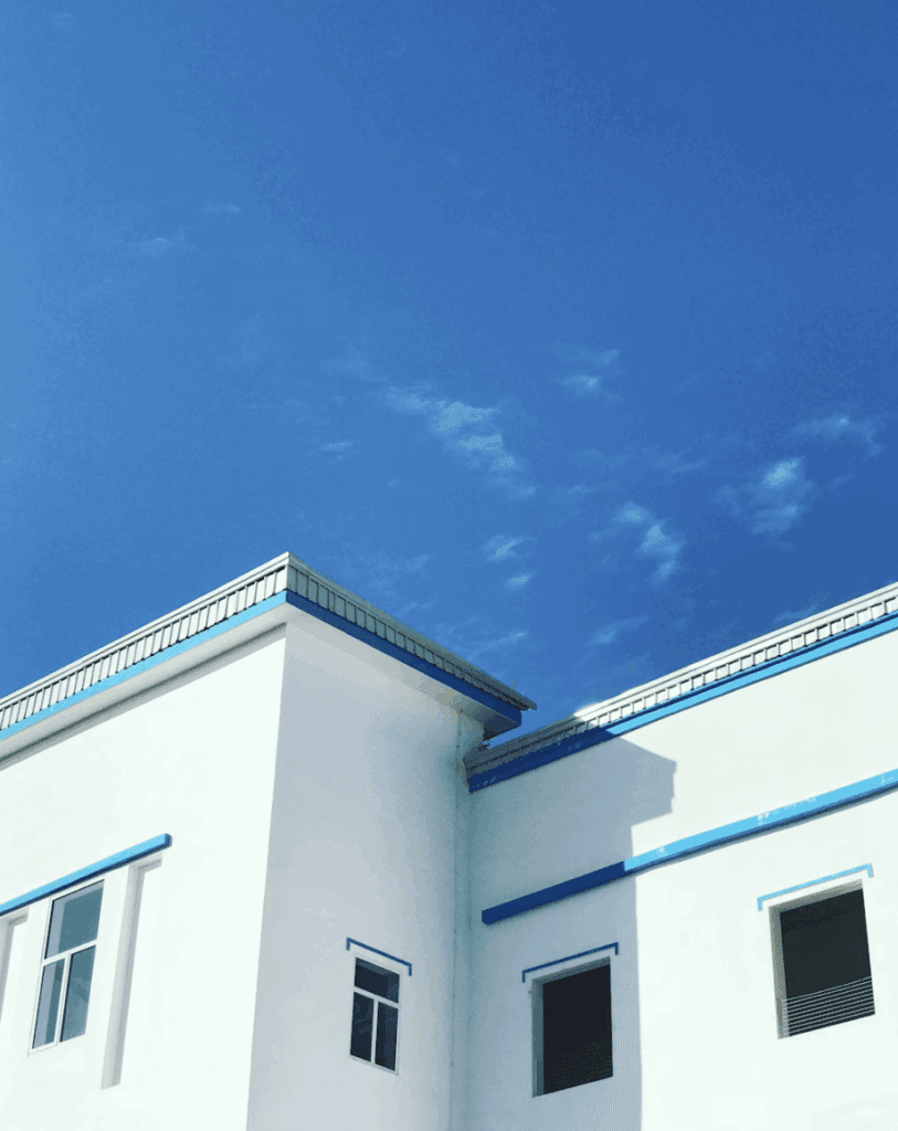 This photo shows house roof beneath bright sunlight clear sky.