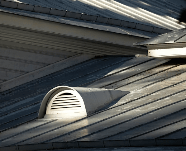  This image shows a ventilation vent on a metal roof.